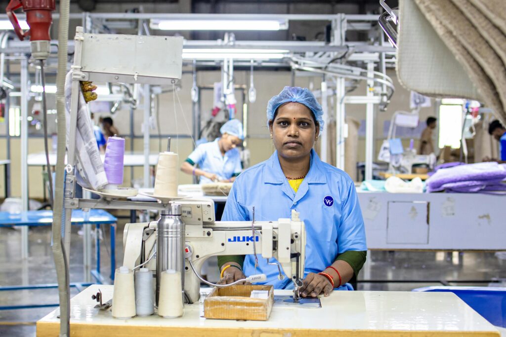 Portrait of a focused female textile worker operating a sewing machine in a factory setting, showcasing industrial precision.